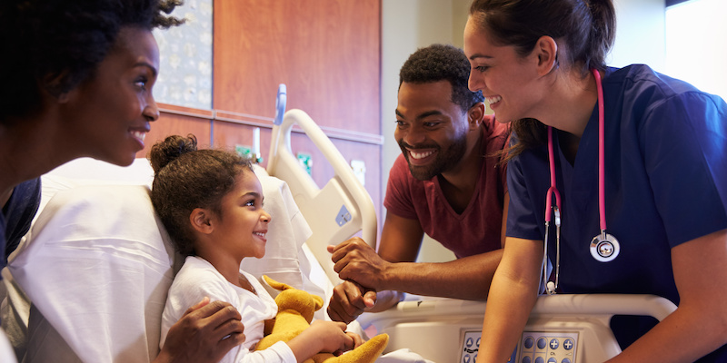 Pediatrician Visiting Parents And Child In Hospital Bed